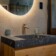 Revonia underground house luxury bathroom vanity – stone sink with gold tap and round LED mirror in earth-sheltered home