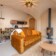 Revonia underground house living room – arched vault interior with orange sofa, wood stove and dining area in modular earth home